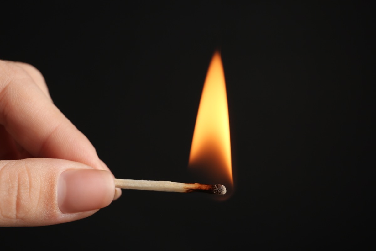 Hand holding a lit match