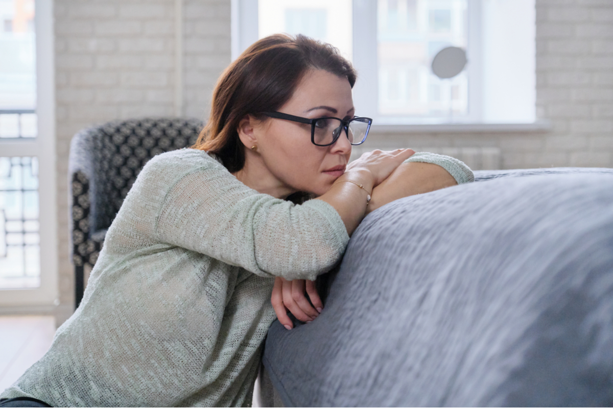 Depressed mature woman sitting on the floor at home