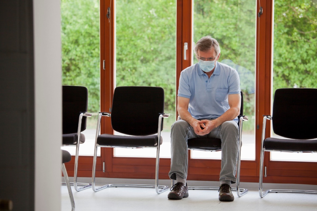 older white man with face mask sitting in waiting room