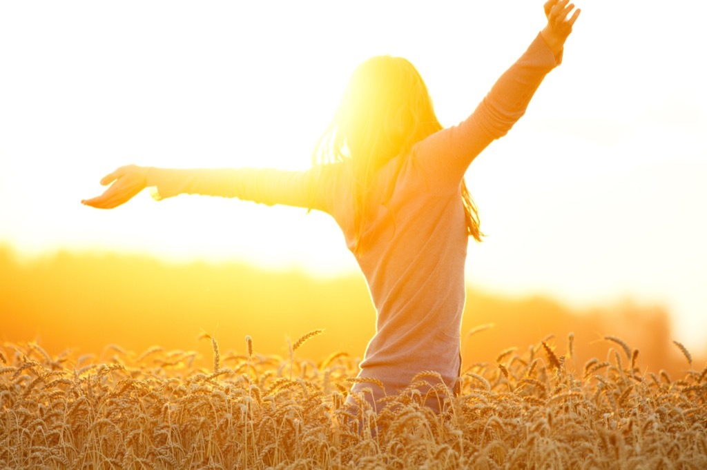 an optimistic woman in a field on a sunny day