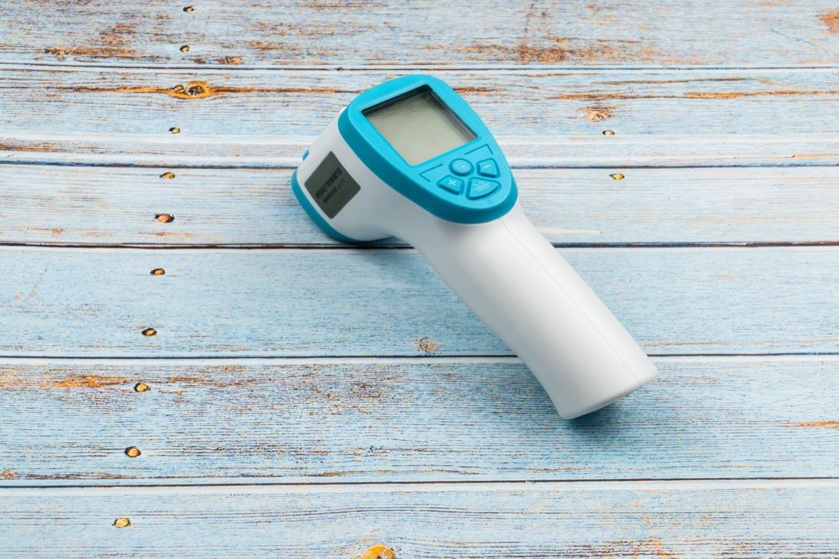 Non-contact infrared thermometer isolated on wooden background to measure a body temperature.