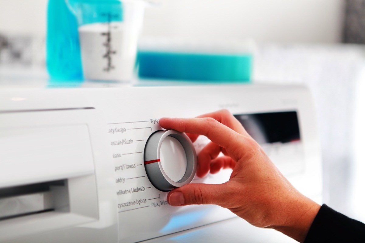 Woman changing dial on washing machine