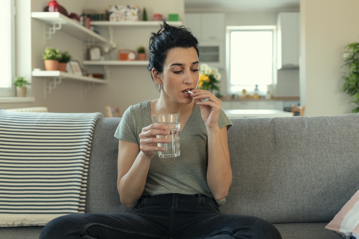 Woman taking tablet with glass of fresh water. Close up of woman holding a glass of water and medication in her hand