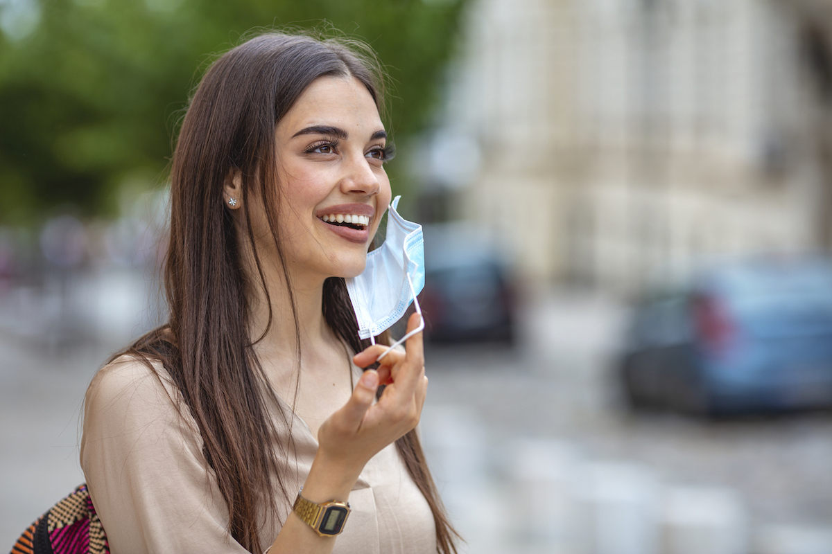 Woman taking off mask outdoors