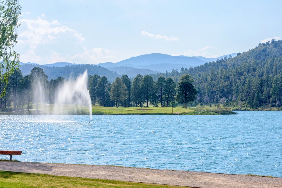 fountain in a blue lake with mountains in the background