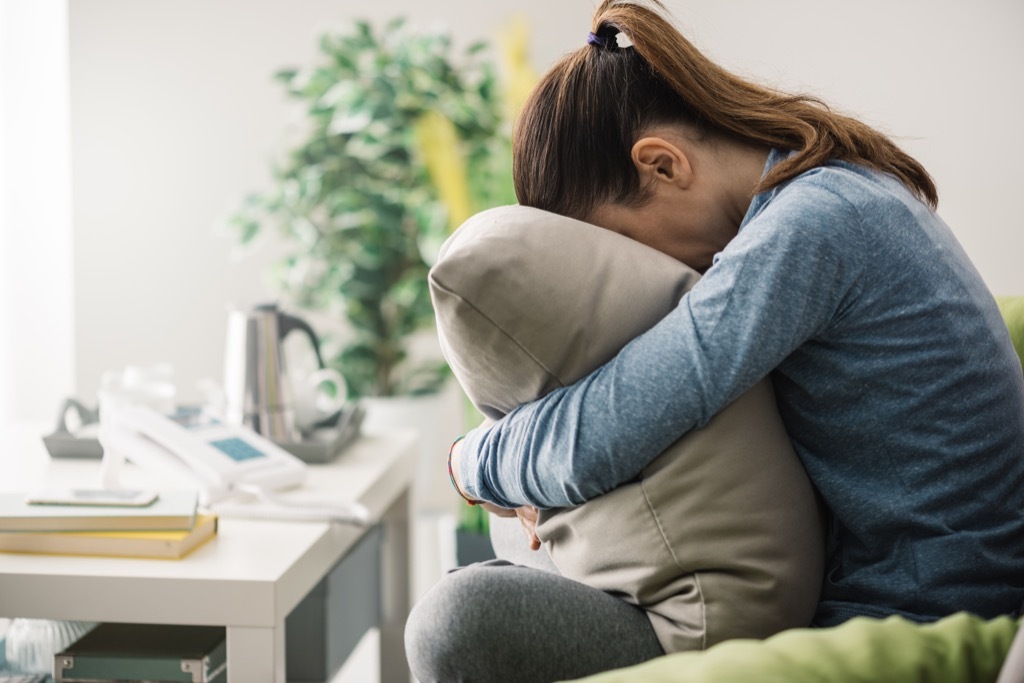 woman alone on couch crying into pillow {Holiday Depression}