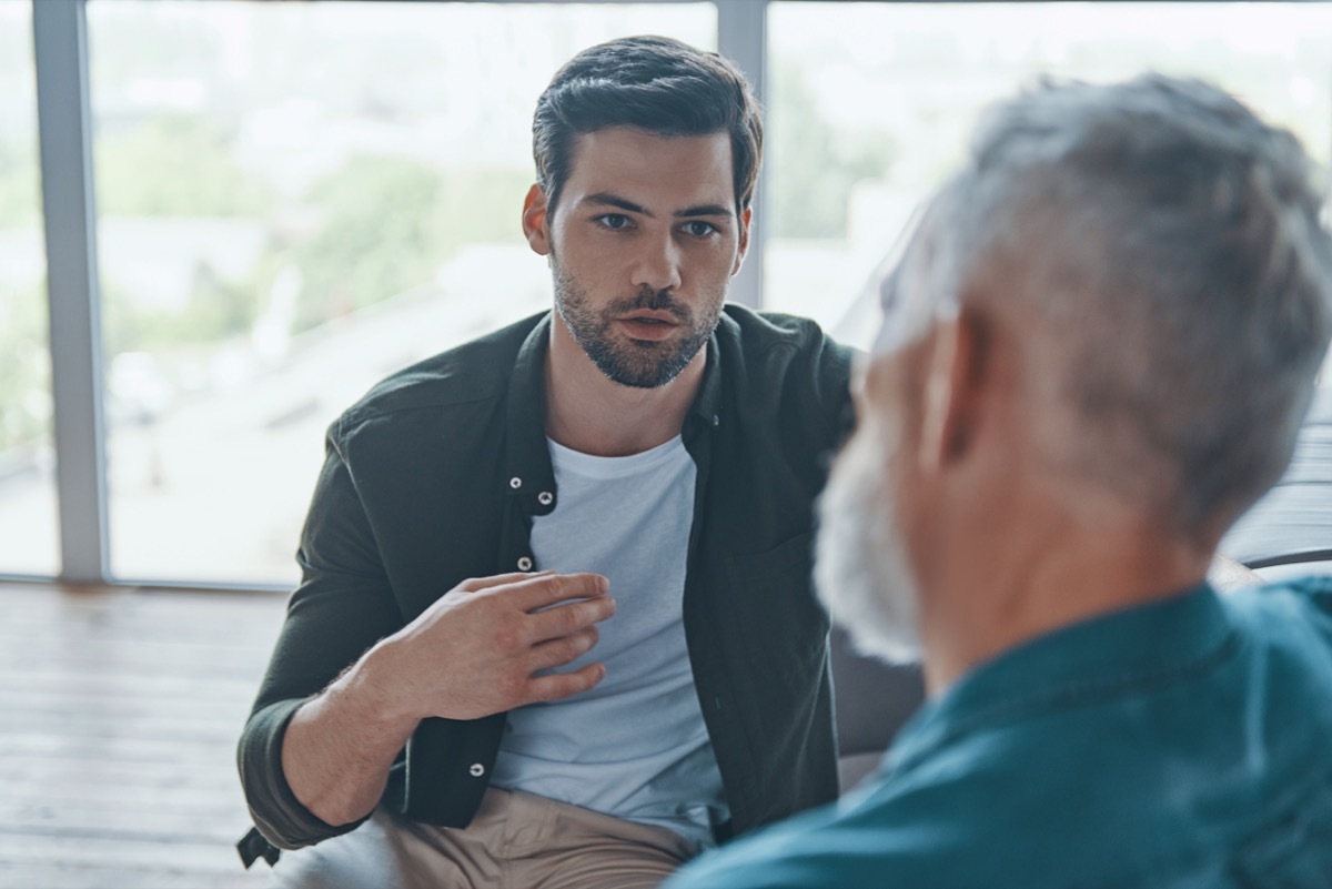 young man talking to his senior father while spending time at home together