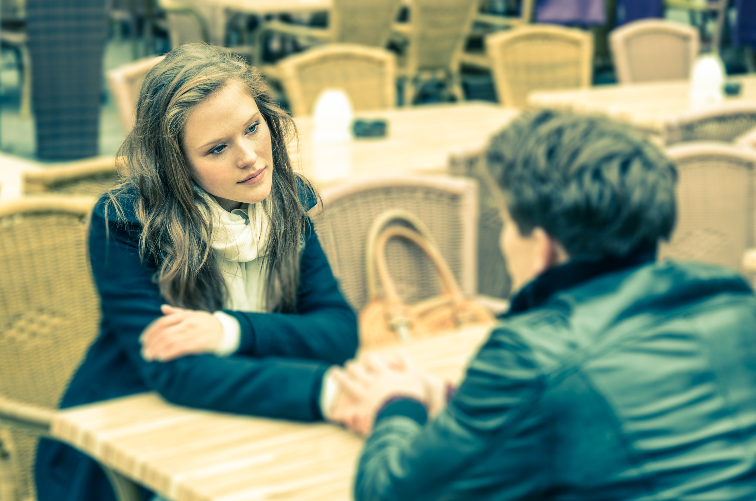 woman holding man's hand from across a table - deep questions to ask your crush