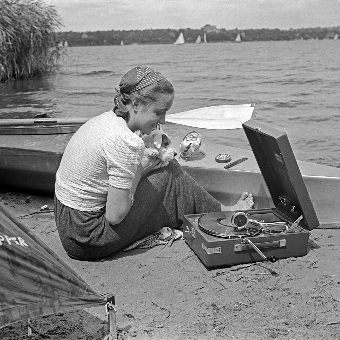 a woman and her dog listen to a portable gramophone