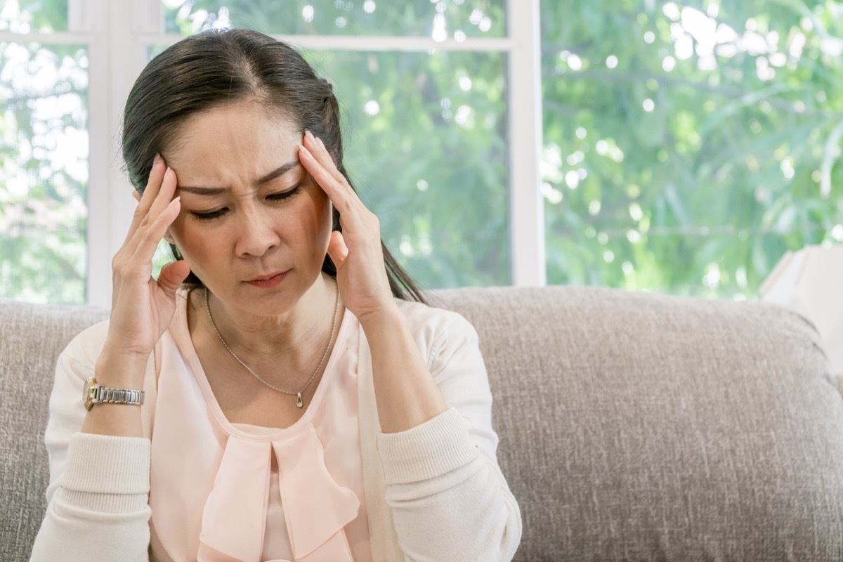 Asian woman sitting on the sofa and having an headache