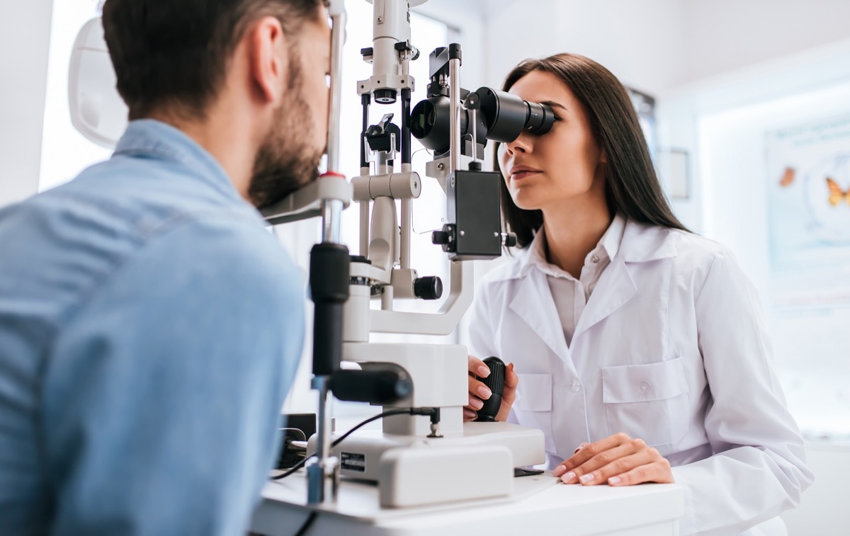 female doctor ophthalmologist is checking the eye vision of young man in modern clinic.