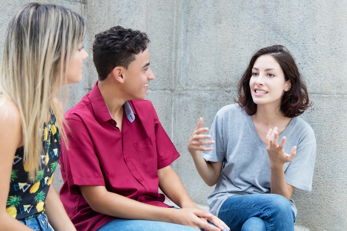 Three young adults in discussion outdoors in the summer