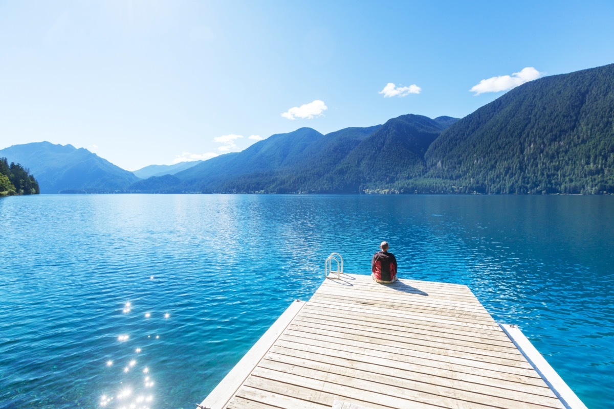 man sits on a pier at lake crescent in washington