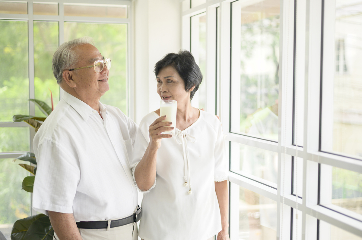 Happy elderly couple drinking milk and spending time together at home