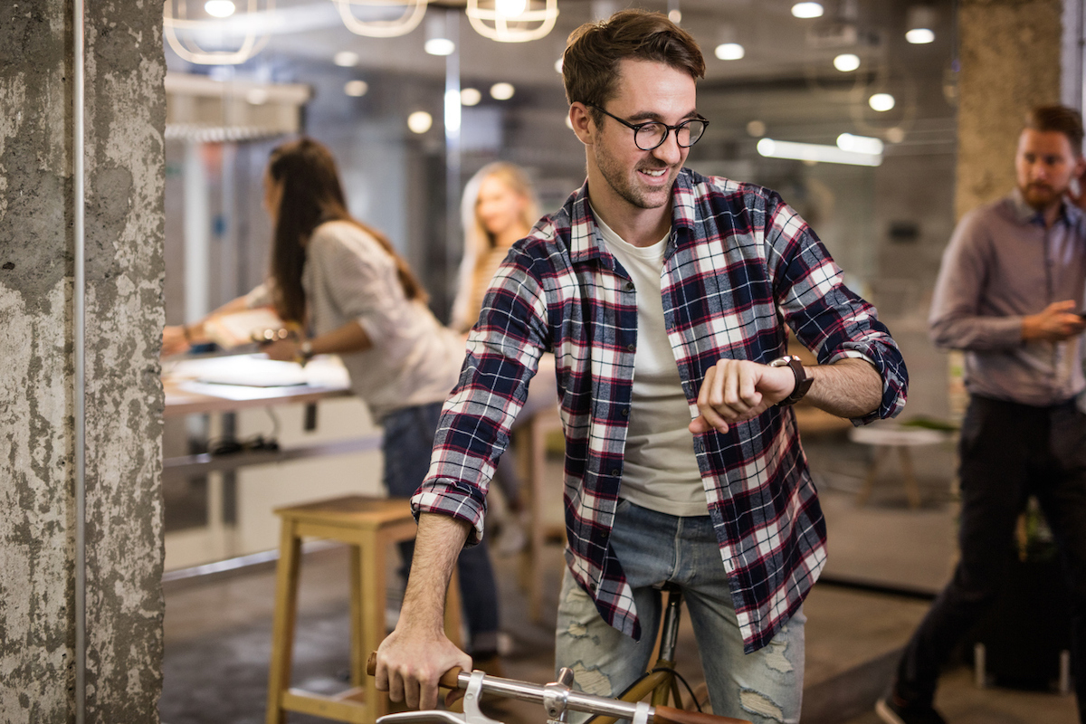 White man leaving work early after checking his watch in casual workplace