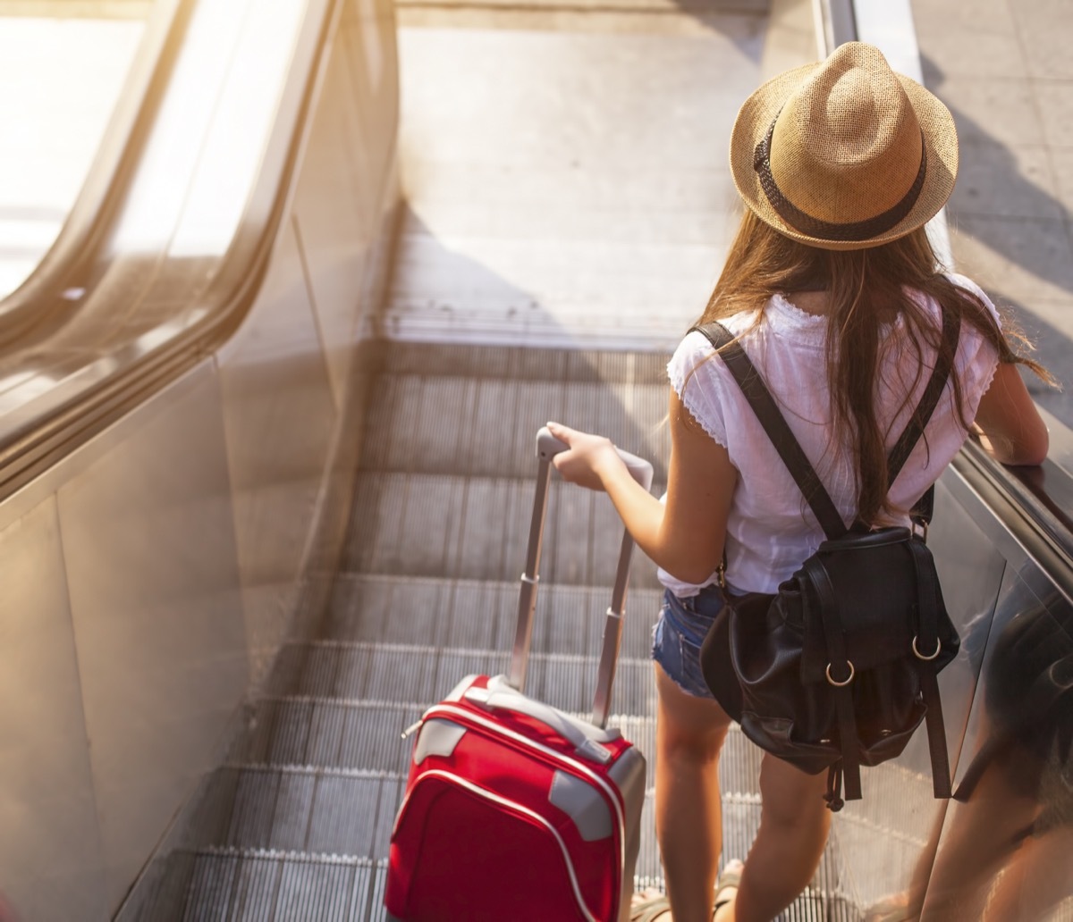 girl with suitcase on escalator