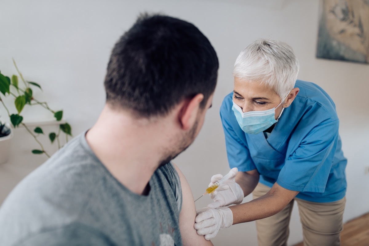 Mature female nurse injecting a Covid-19 vaccine to a mid adult patient.