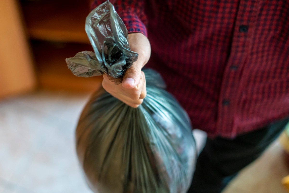 man in red shirt holding black trash bag