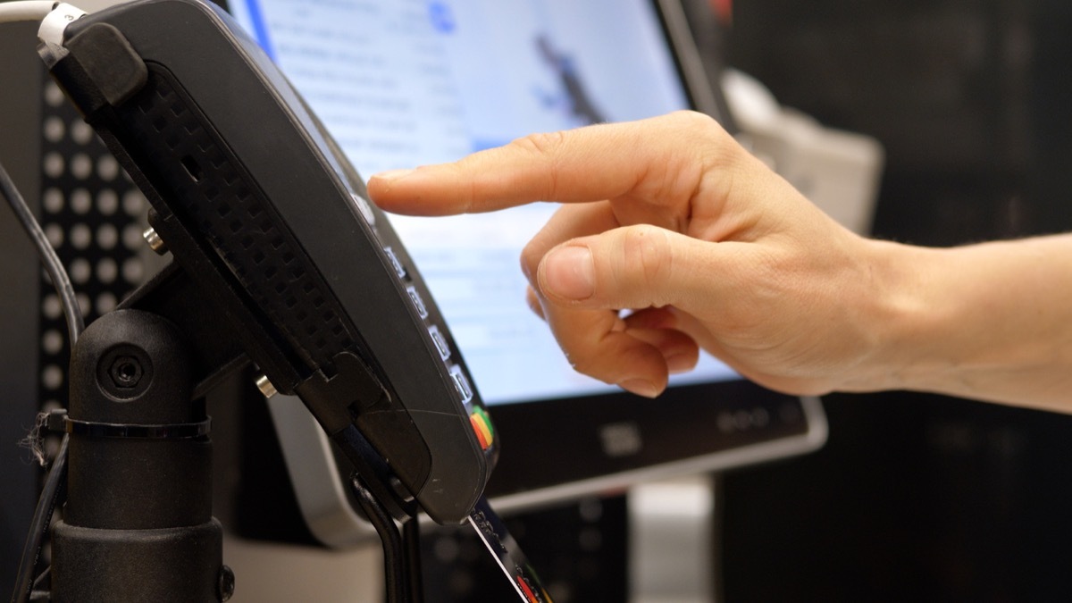 Close up of person hand inserting a credit card in the terminal and entering the pin code. Equipment for paying with bank cards without the use of cash. Payment through the terminal of purchases.