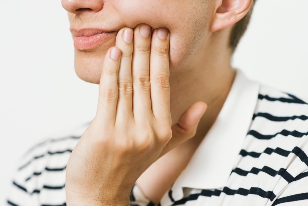 person who has a toothache holding their jaw, ways your body changes after 40