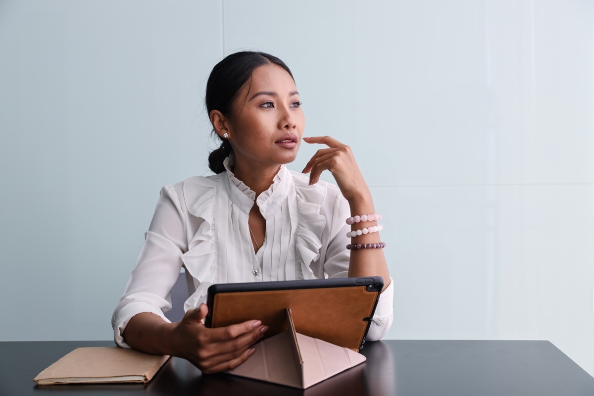 Woman looking outside from her desk with tablet