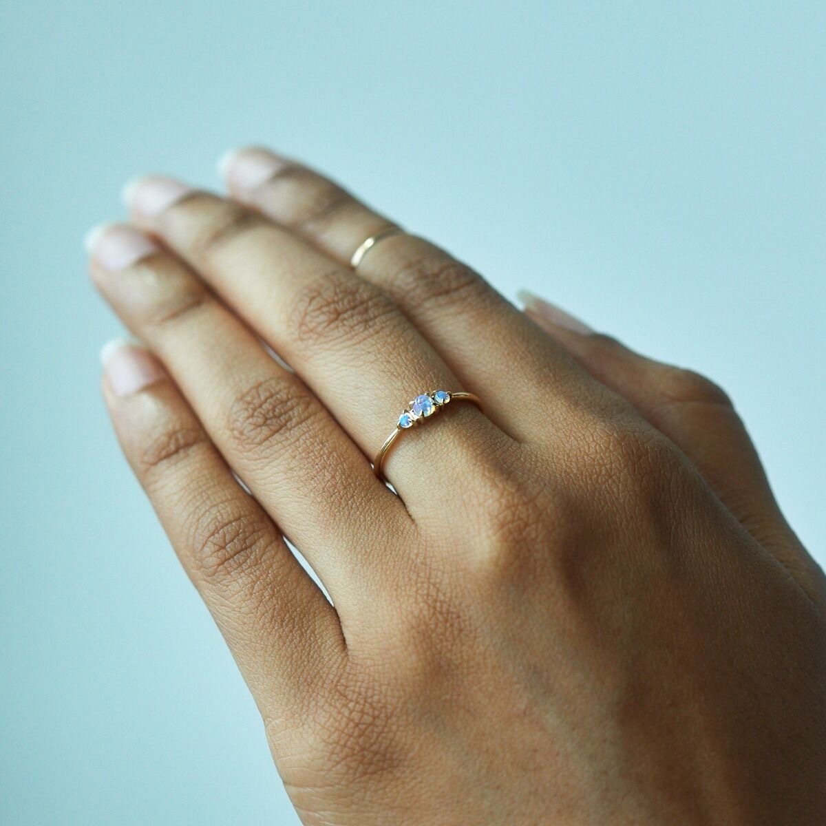 woman's hand wearing thin opal ring