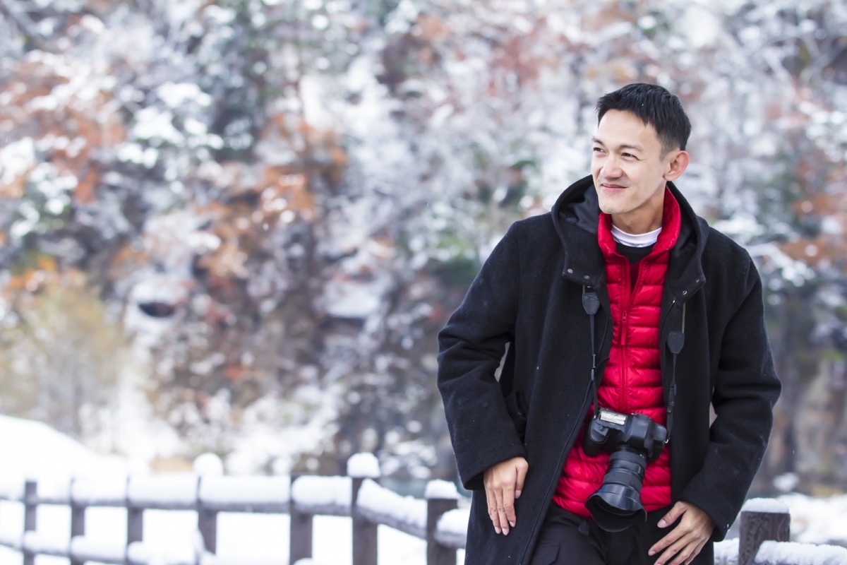 man wearing a black topcoat and a bright red vest