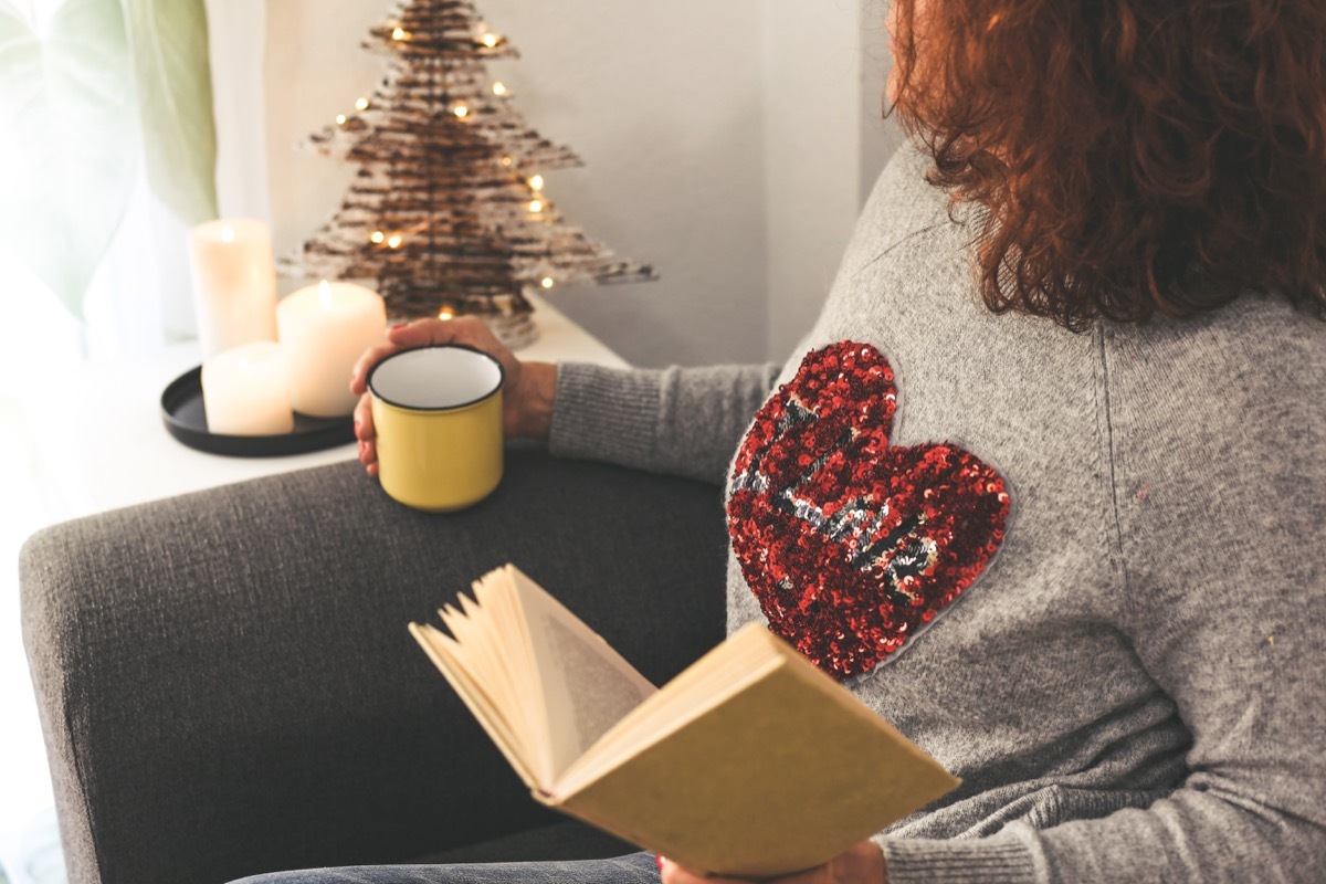 Woman wearing sequin heart t-shirt while drinking tea and reading a book