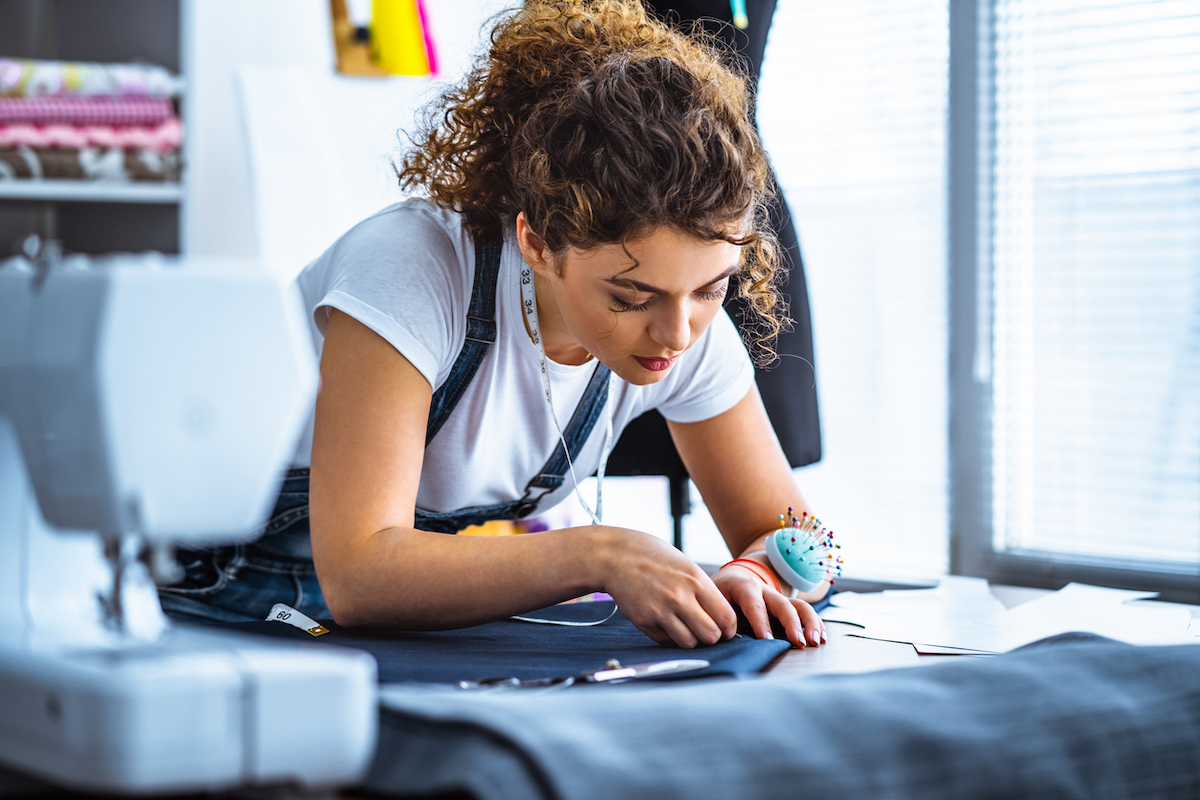 Young female tailor working near the sewing machine