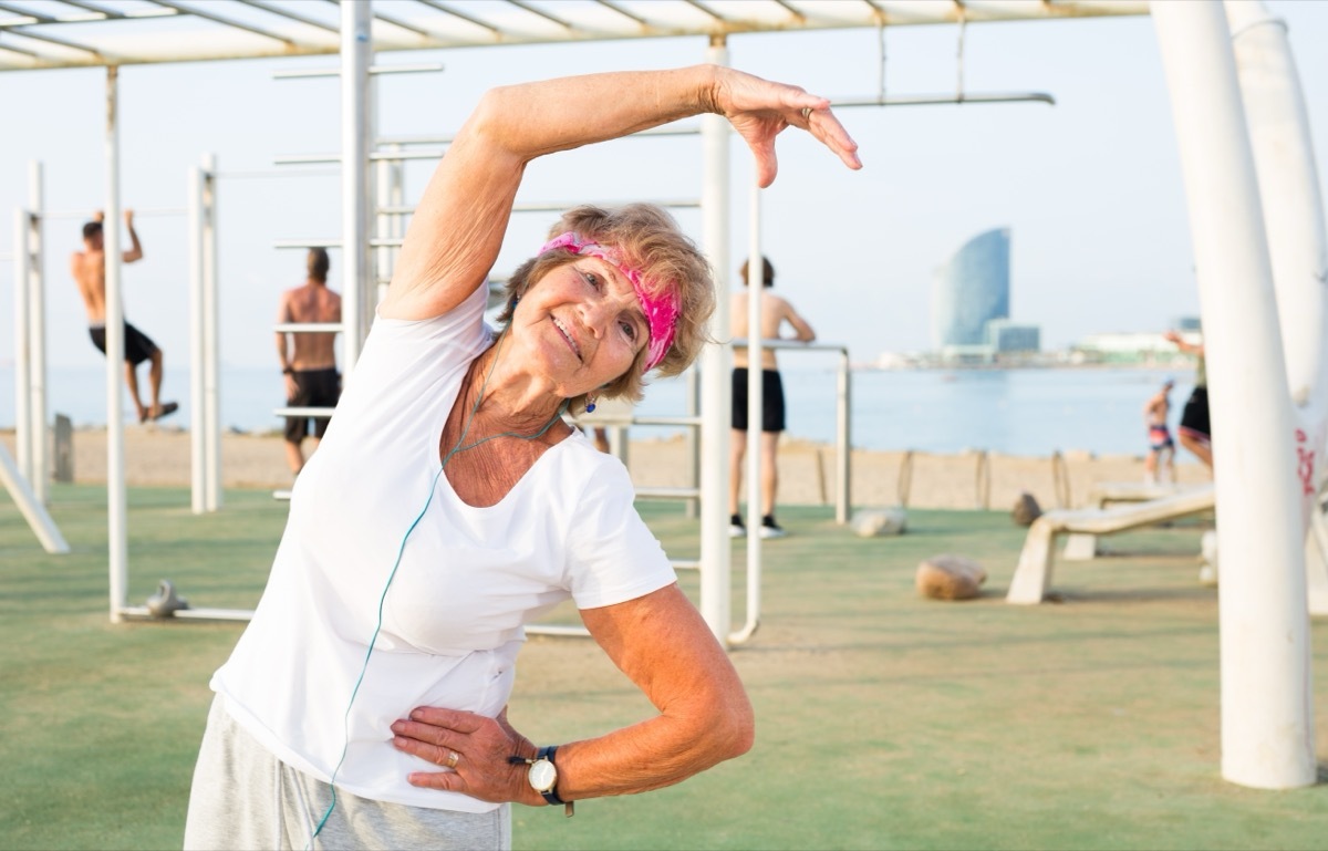 Old woman doing fitness exercises outdoors