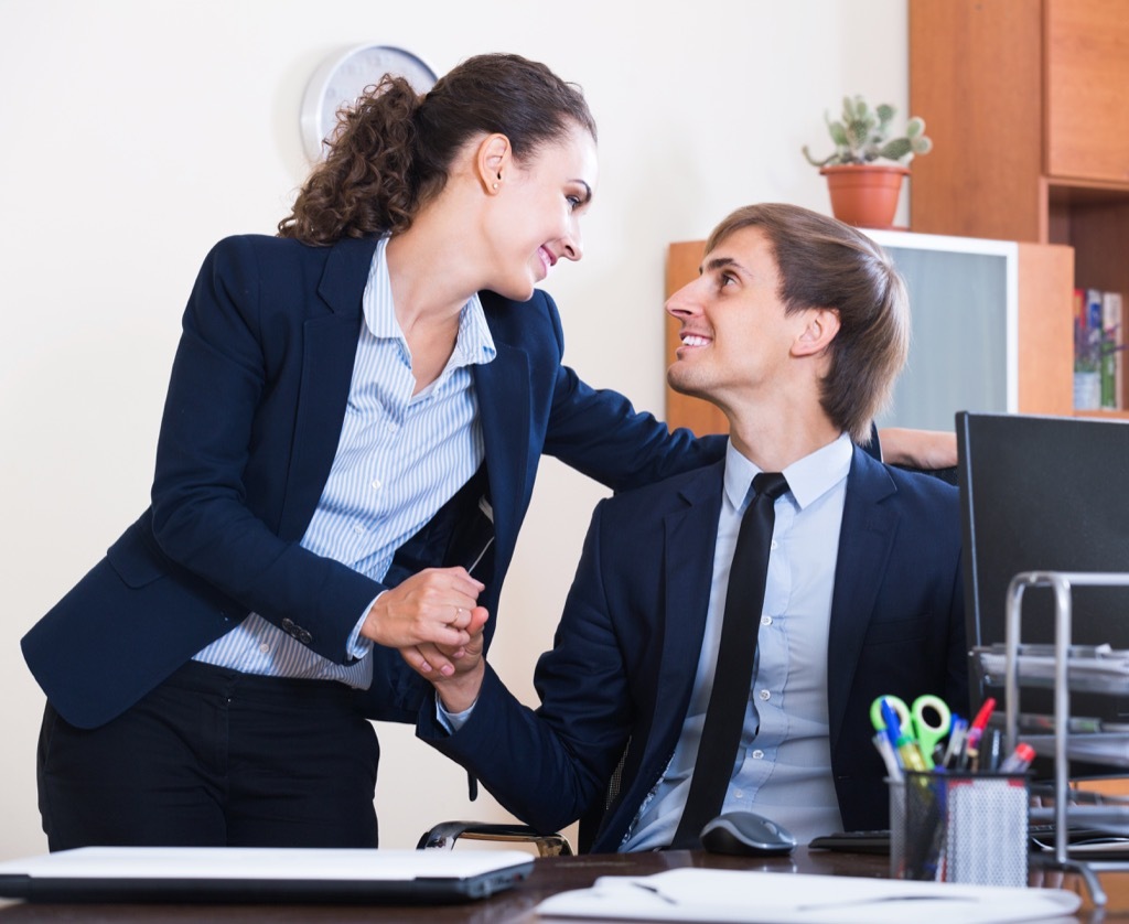 woman holding a man's hand at work, how to tell if a girl likes you