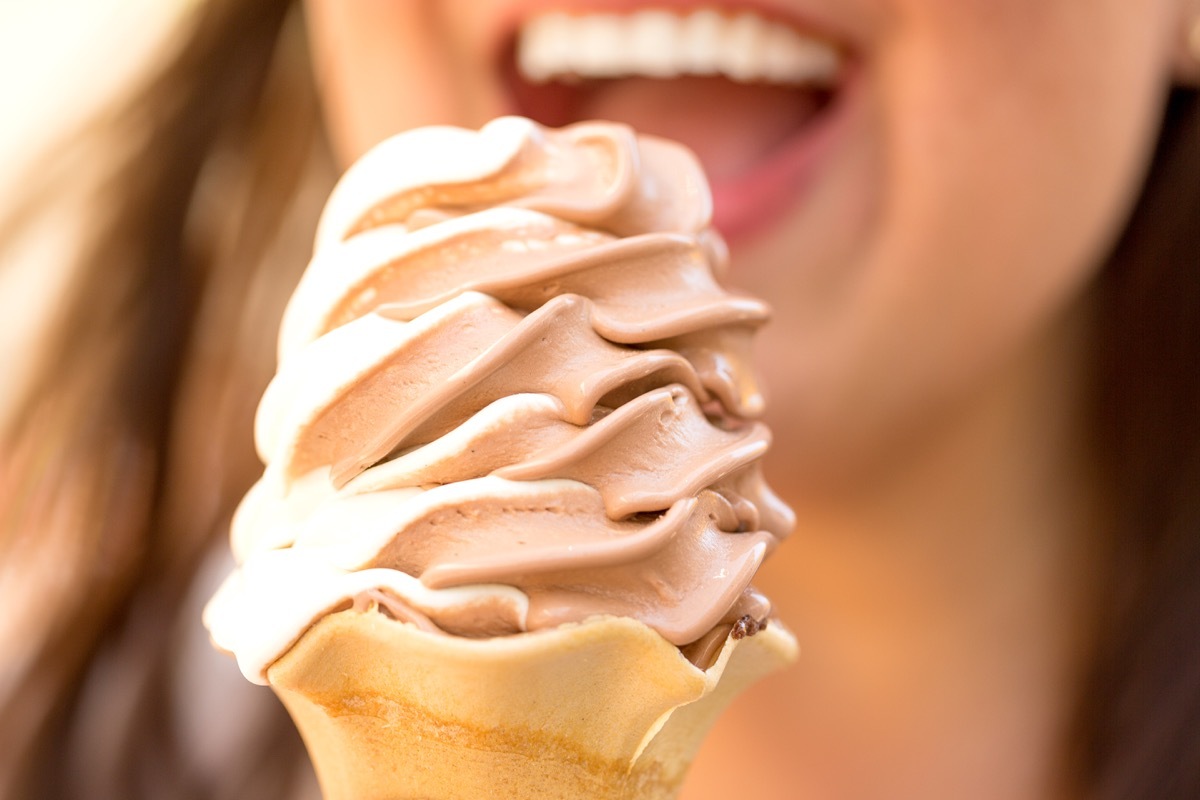 Woman eating chocolate and vanilla ice cream on a cone