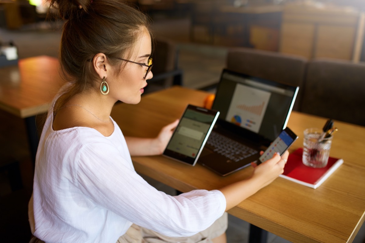 woman in glasses working with multiple electronic internet devices