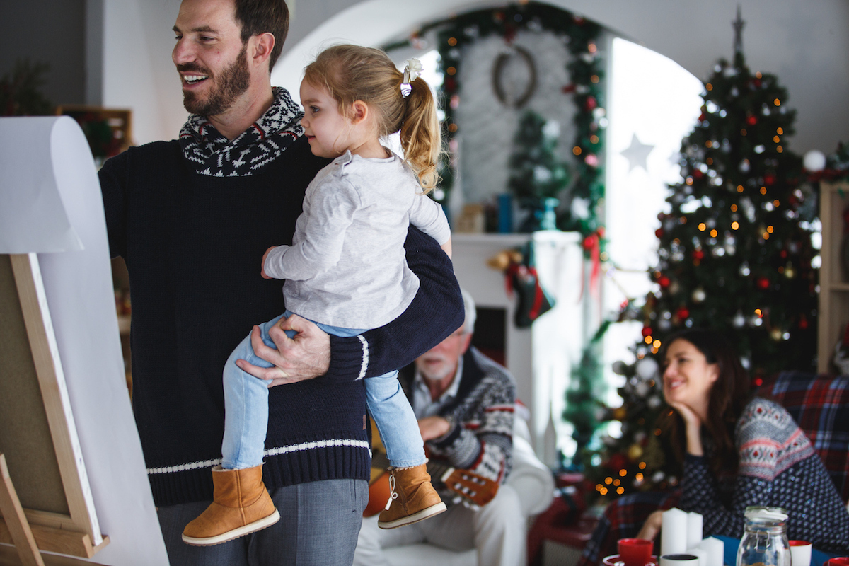 Mid adult man and his little daughter are drawing together at home during Christmas time playing Pictionary