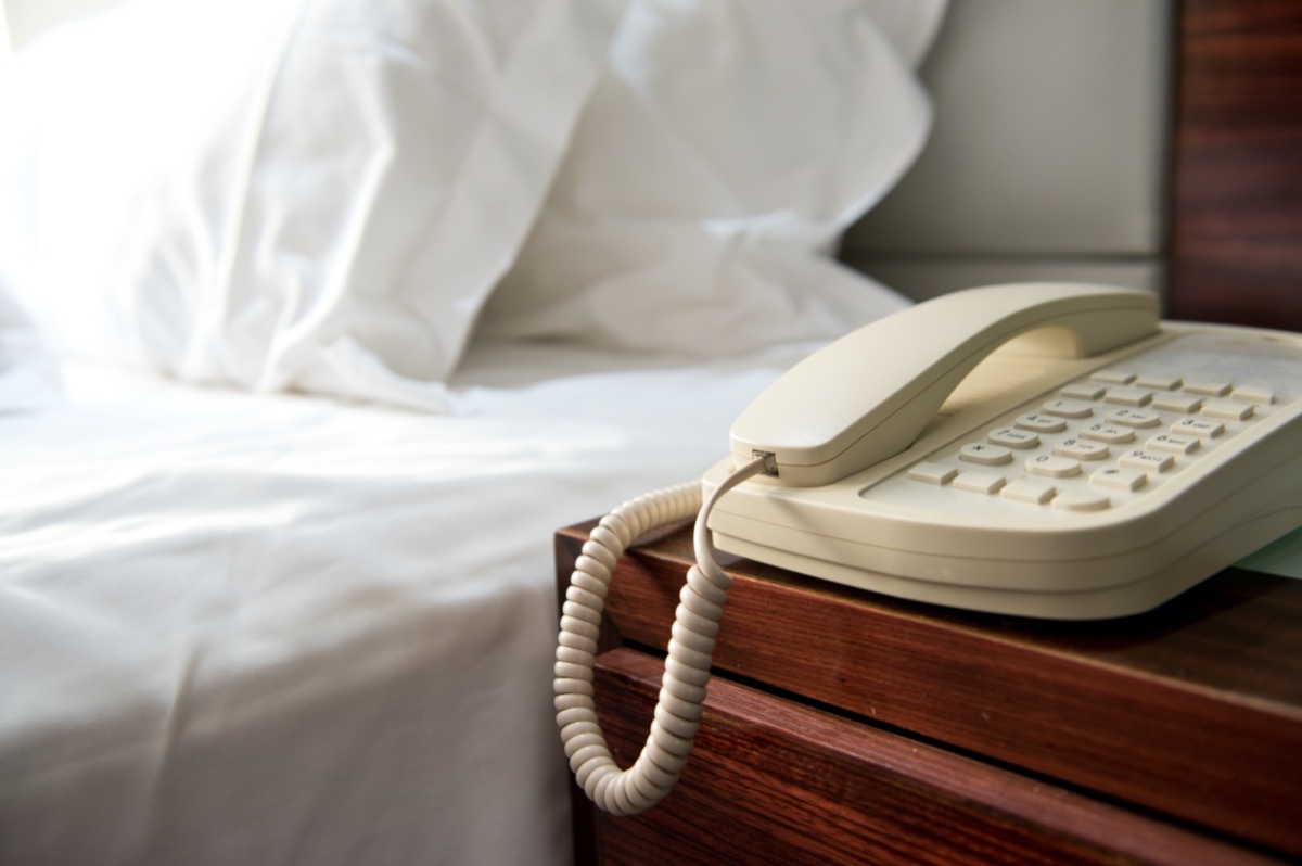 phone on a night desk near the bed in a hotel room