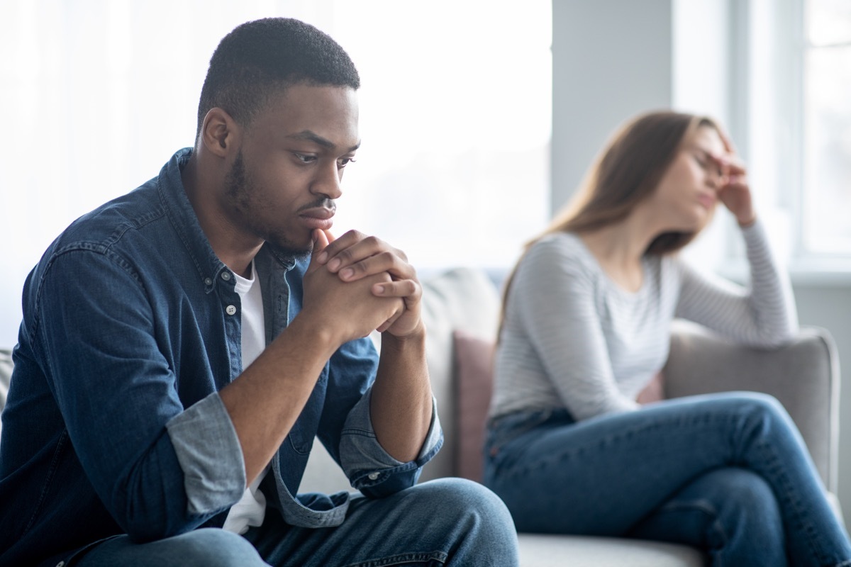 young man and woman in a couple looking upset at one another while sitting on couch