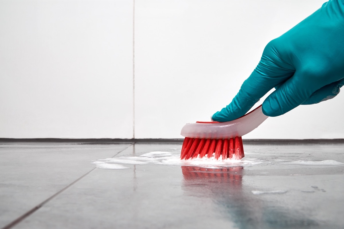 Scrubbing kitchen floor with brush