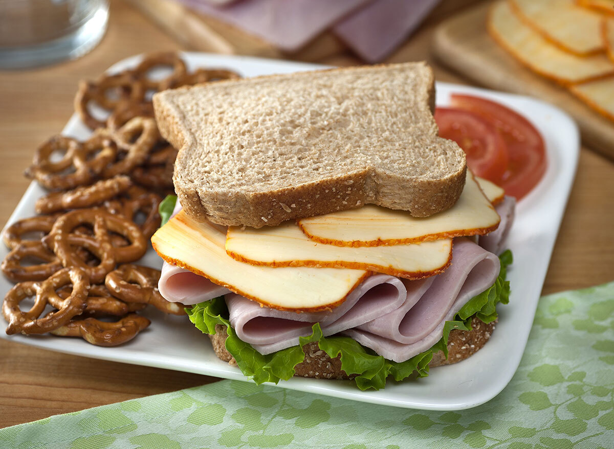 Muenster cheese and ham sandwich with side of pretzels on a plate