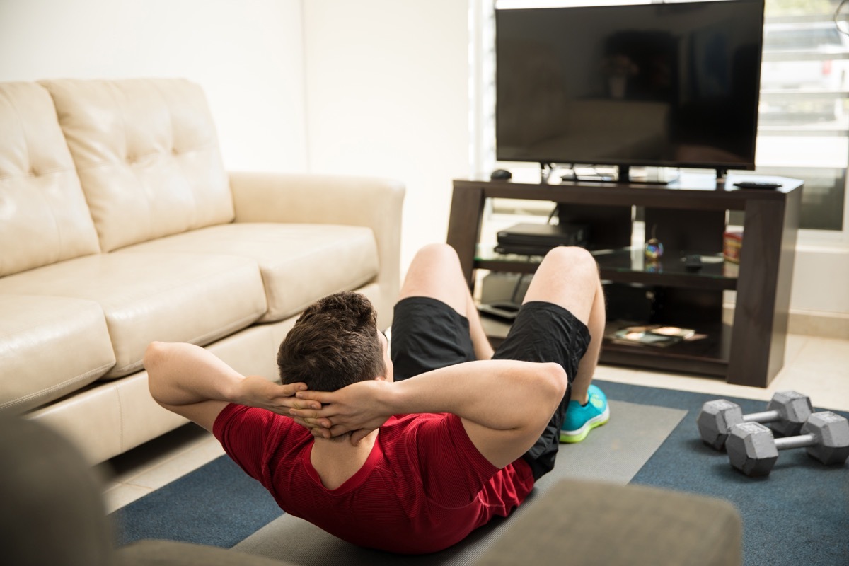 Man doing crunches in front of the TV in the living room