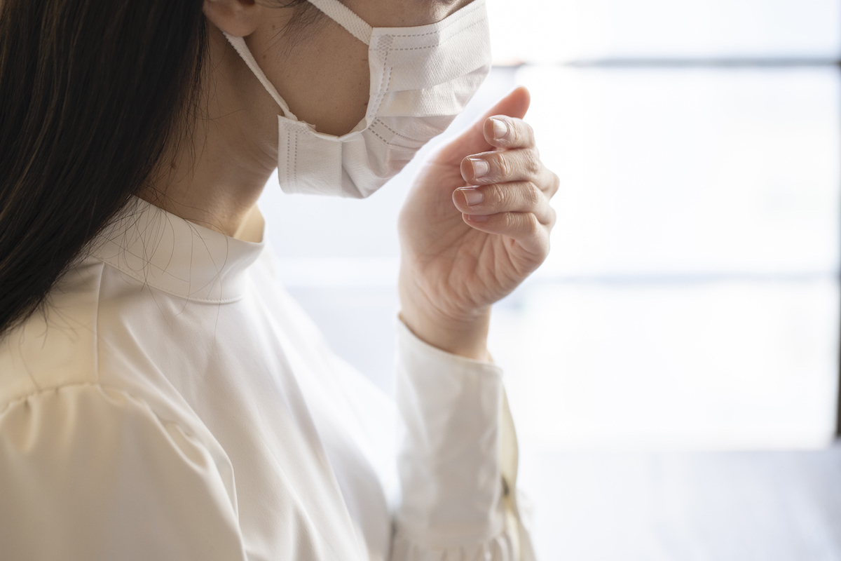 Close up face of young woman wearing mask and coughing