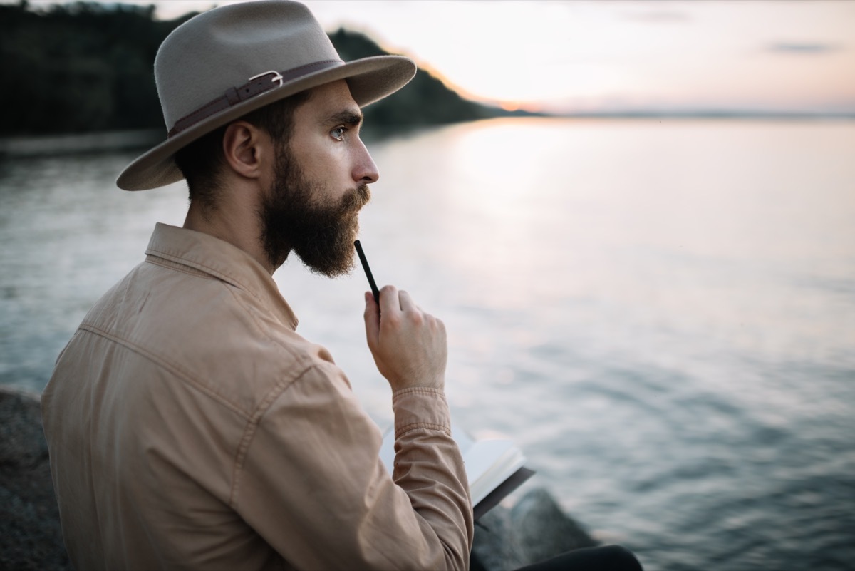 Man writing a poem by the water