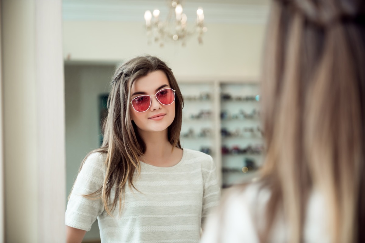 young woman with brown hair trying on sunglasses