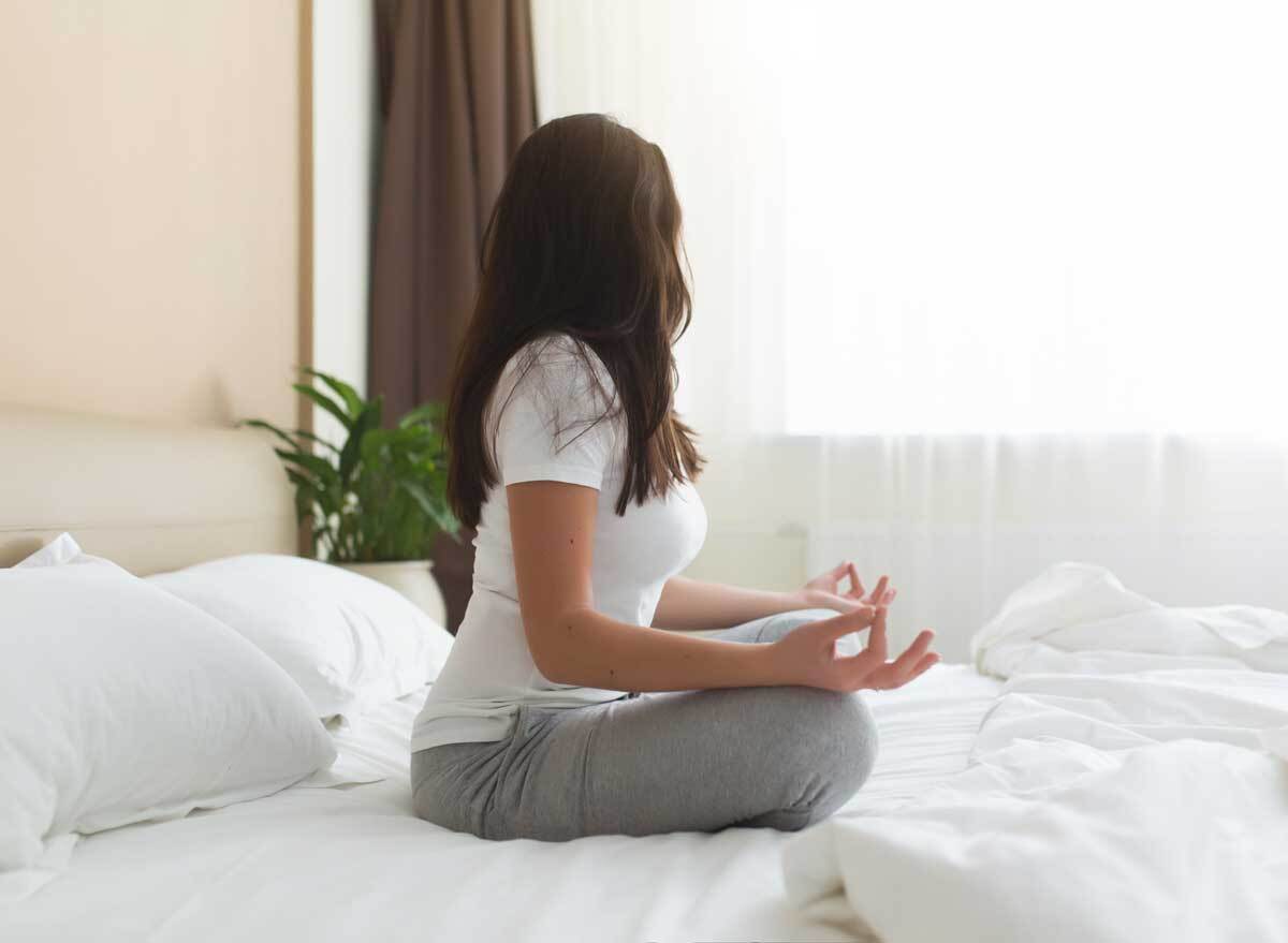 Woman meditating on her bed