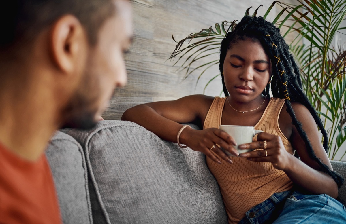 Shot of a young woman sitting with her boyfriend in the living room at home and looking upset