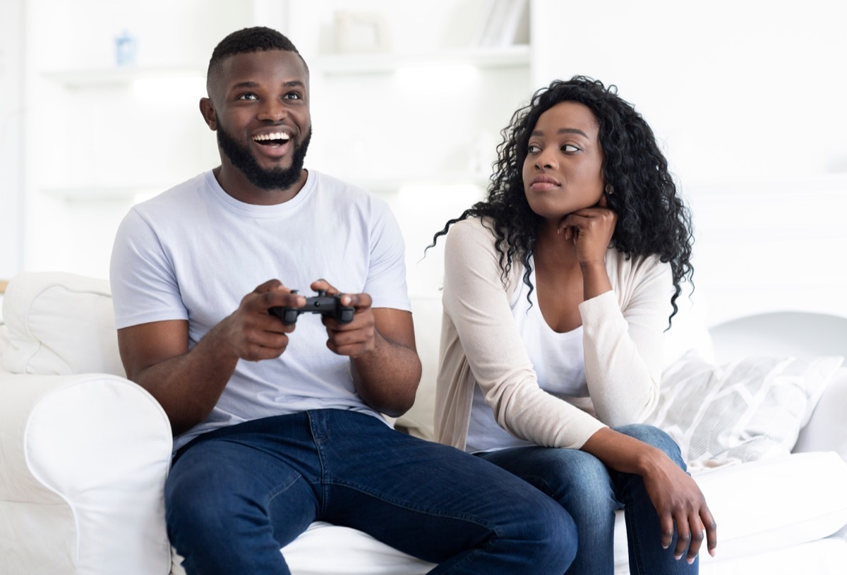 bored woman looks at man playing video games