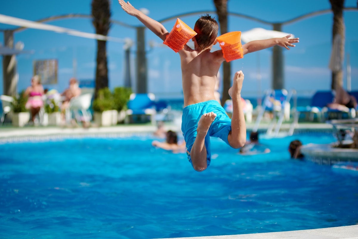 young white boy in swimmies jumping into pool