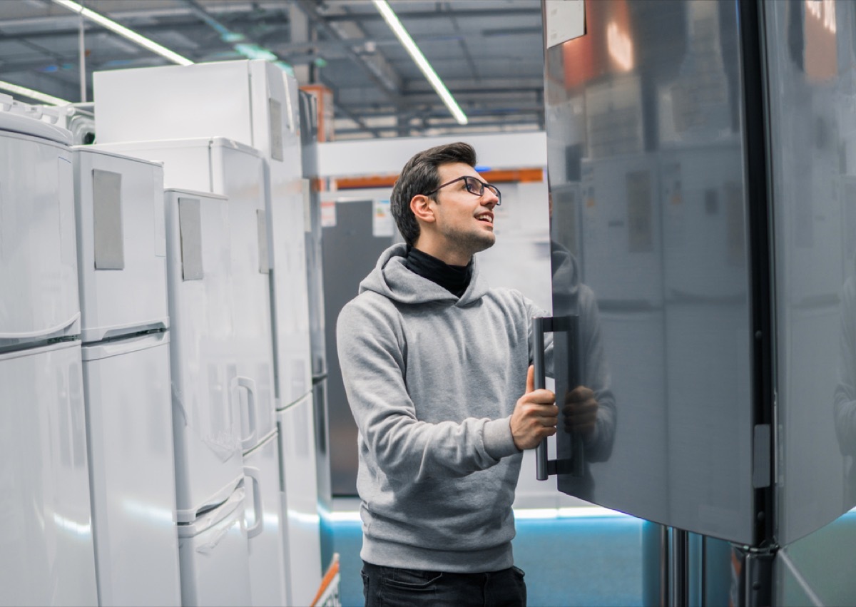 white man opening a fridge door in refrigerator section at store