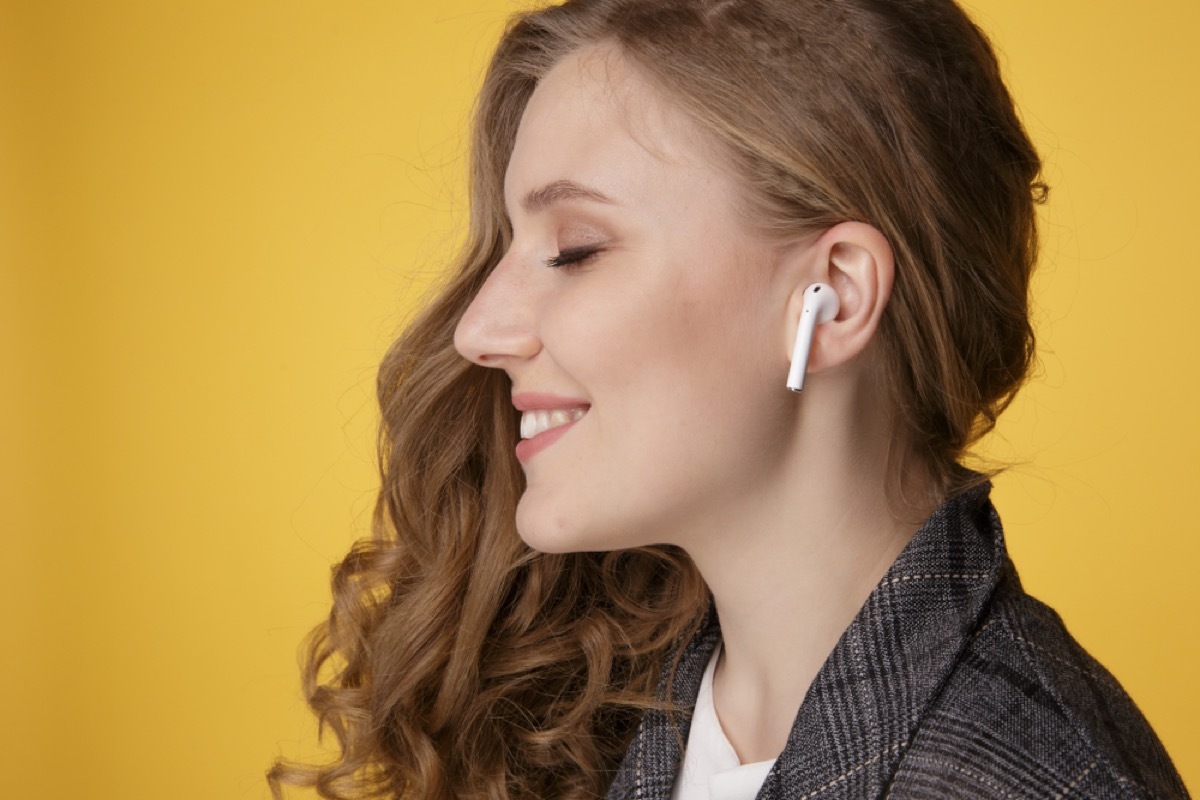 young white woman shown from profile with airpods, wireless headphones, in her ears