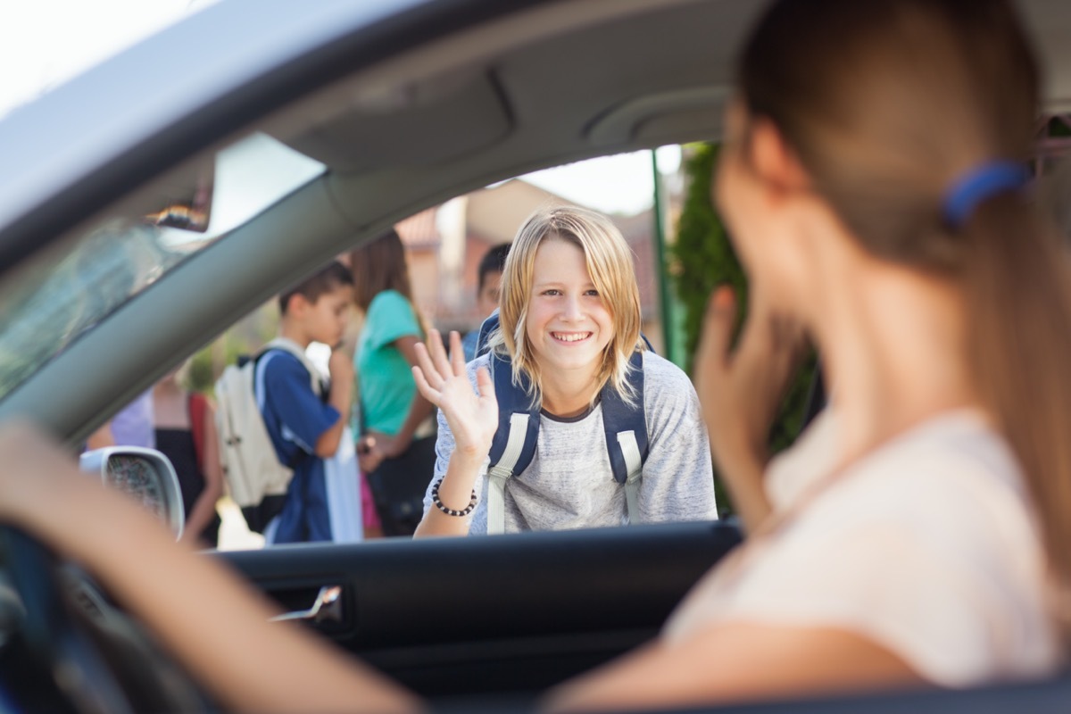 Mother waving goodbye at her son before school.