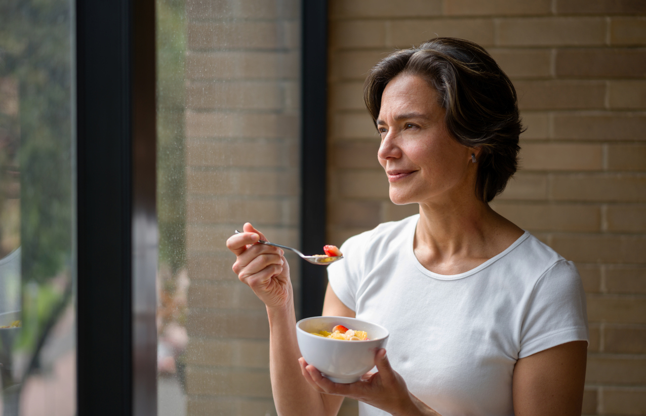 Woman eating and looking at the window.